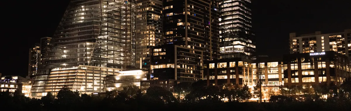 Illuminated skyscrapers reflecting in the river at night in downtown Austin, Texas.