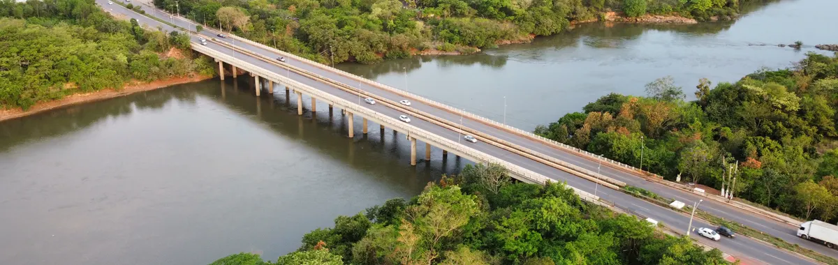Drone shot capturing a bridge over a river surrounded by lush greenery in Cuiabá, MT, Brazil.