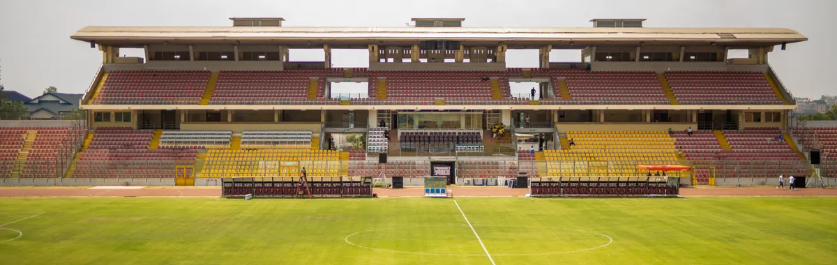 A wide view of the empty Baba Yara Sports Stadium in Kumasi, showcasing its structure and green field.
