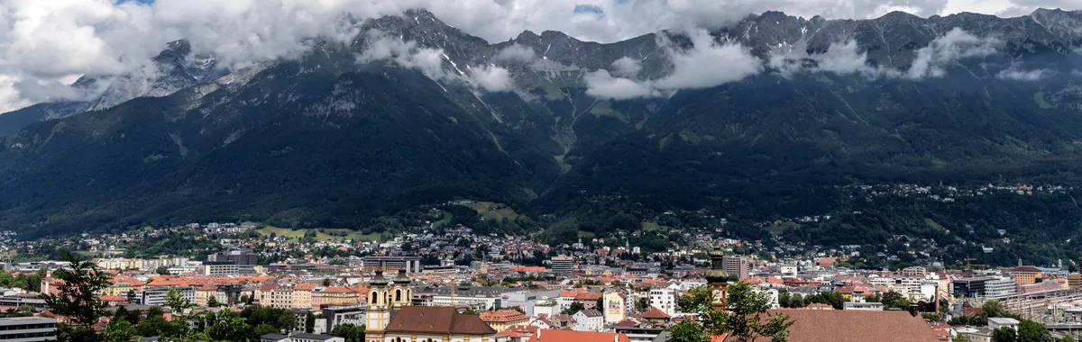 A breathtaking aerial view of Innsbruck, Austria, framed by majestic mountains and vibrant urban life.