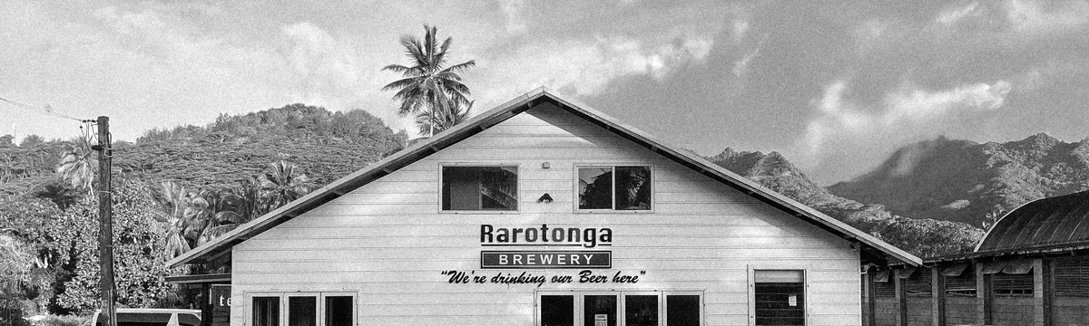 איי קוק: Black and white photo of Rarotonga Brewery with mountains in the background.