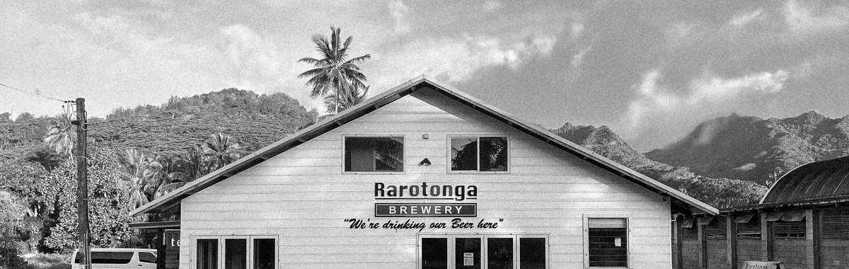 איי קוק: Black and white photo of Rarotonga Brewery with mountains in the background.