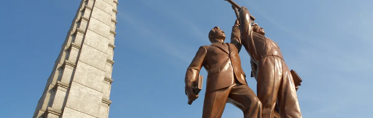 קוריאה הצפונית: Low angle view of Juche Tower and worker statues against a clear blue sky in Pyongyang, North Korea.