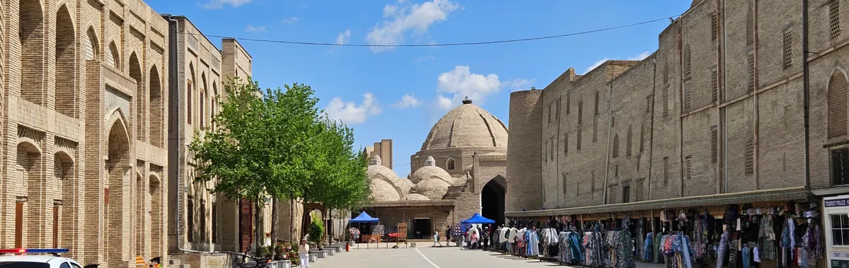 A picturesque view of the historic market street in Bukhara, Uzbekistan, under a clear blue sky.
