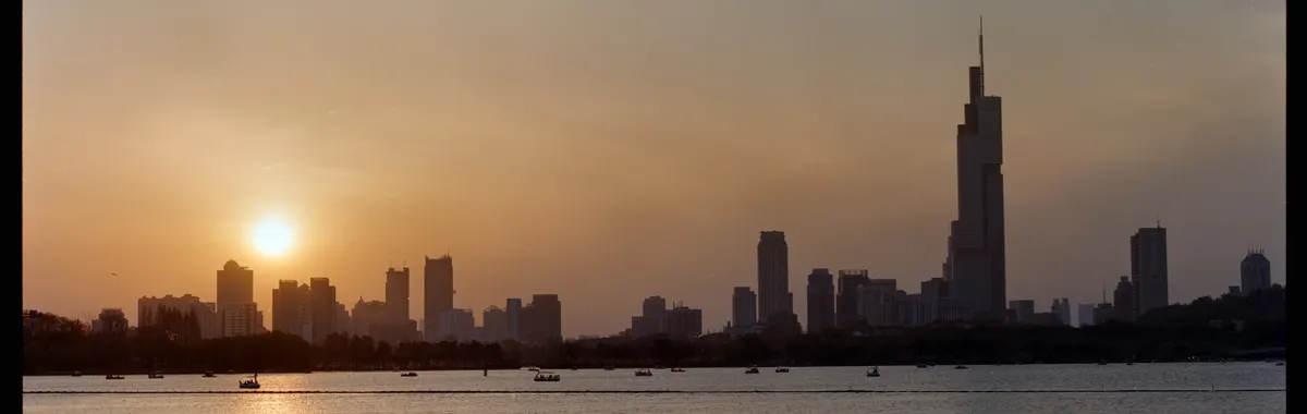 Scenic view of Nanjing skyline at sunset with Zifeng Tower reflecting on Xuanwu Lake.