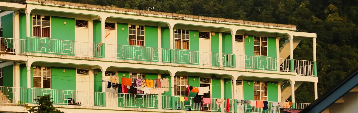 דומיניקה: Vibrant apartment building with laundry on balconies in Portsmouth, Dominica, during sunset.