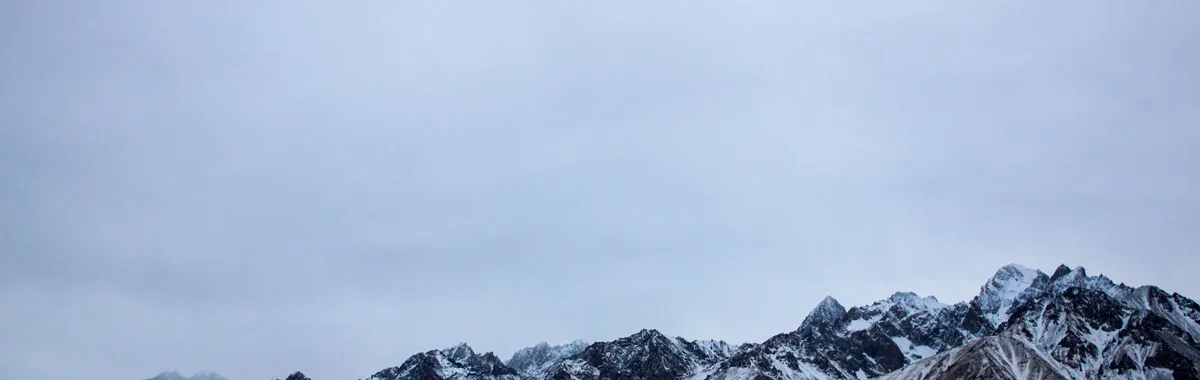 Breathtaking view of snow-covered mountains in Kashgar, Xinjiang, China under a cloudy sky.
