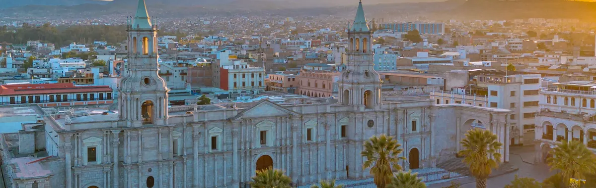 Drone shot of Arequipa's cathedral with El Misti volcano in the background at sunset.