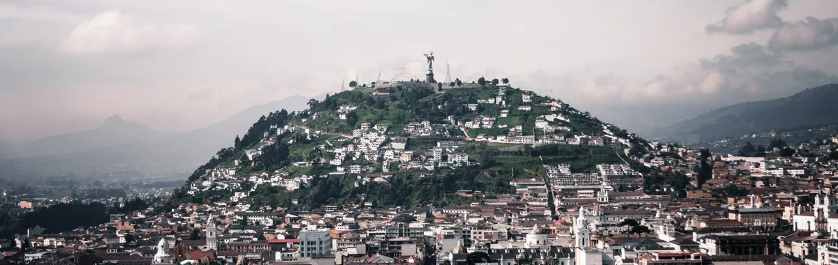 Aerial view of Quito featuring Panecillo Hill and Virgin statue, capturing historic architecture and vibrant cityscape.