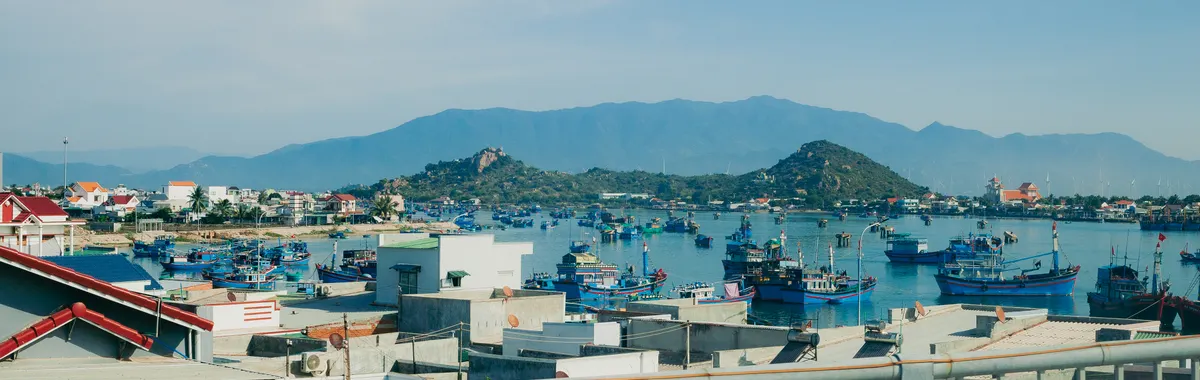 Beautiful view of Vinh Hy Bay with colorful boats and mountains under a clear sky.