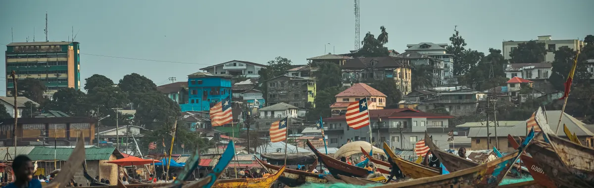 ליבריה: Vibrant scene of fishing boats and urban skyline in Monrovia, Liberia.