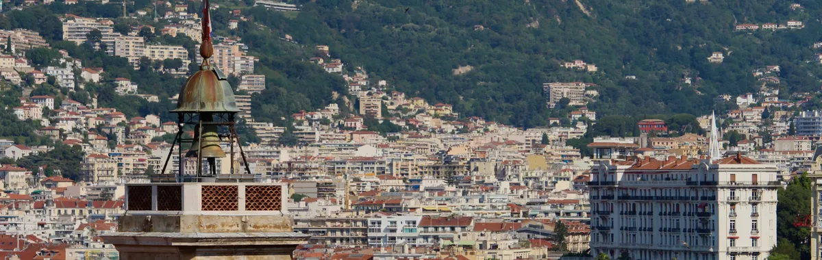 A stunning view of a historic clock tower with the cityscape of Nice, France in the background.