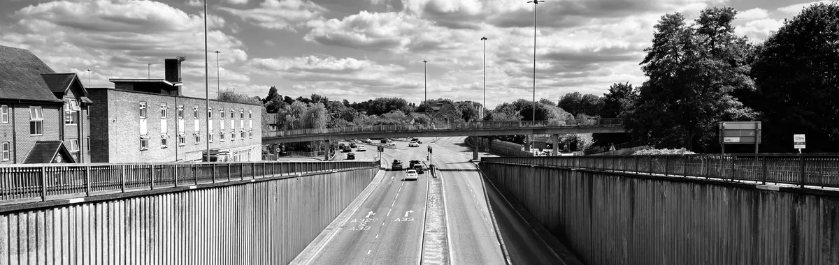 A black and white photograph of a motorway in Reading, England under a bright sky.