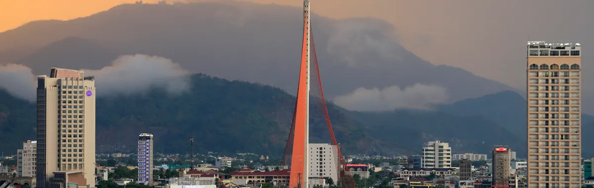 Cityscape of Da Nang featuring the iconic Han River Bridge against a sunset backdrop.