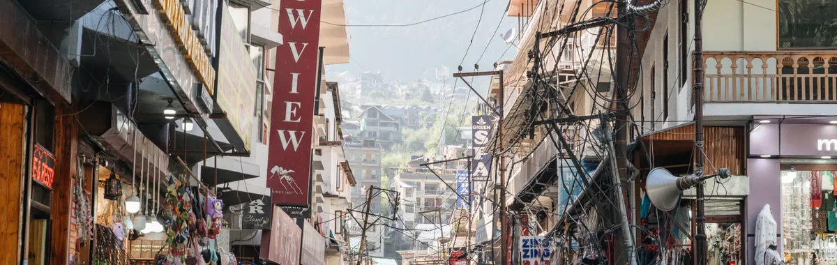 Vibrant street market in Manali, India showcasing local shops and bustling crowds under clear skies.