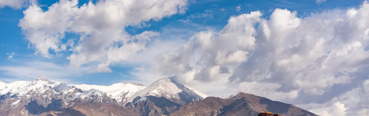 Breathtaking view of Potala Palace amidst mountains and vibrant autumn landscape in Lhasa, Tibet.