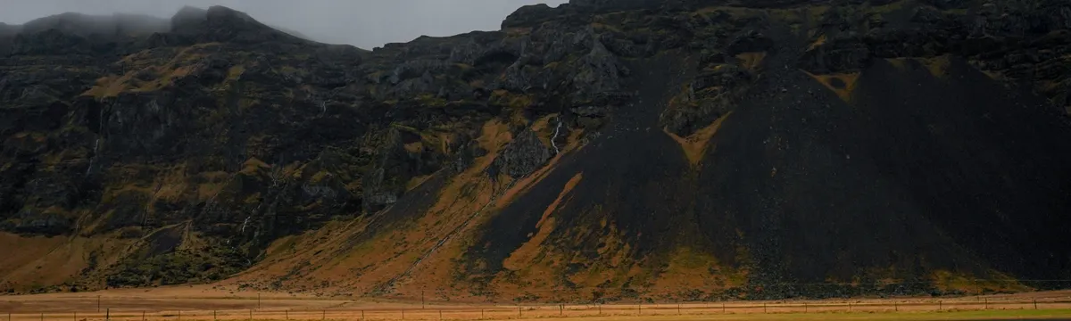 איסלנד: Majestic view of Iceland's rugged hills on a cloudy day, showcasing nature's raw beauty.