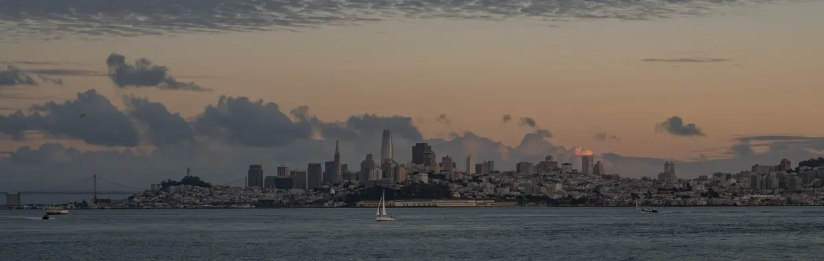 Beautiful view of San Francisco skyline with tranquil waters and a dramatic sunset sky.
