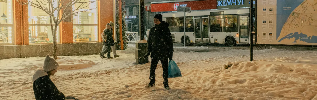 Winter scene in Samara, Russia with people enjoying a snowy evening in the city square.
