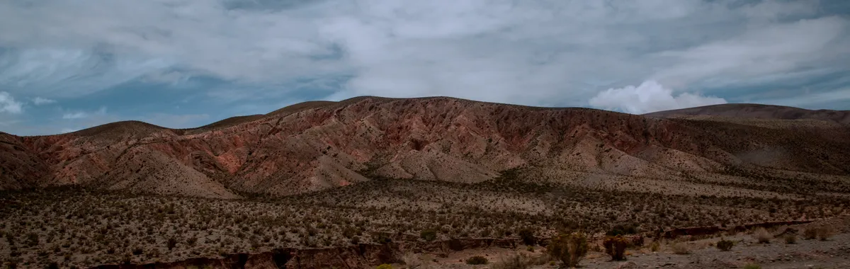 Vast desert landscape with rugged hills and cloudy sky in Salta, Argentina.