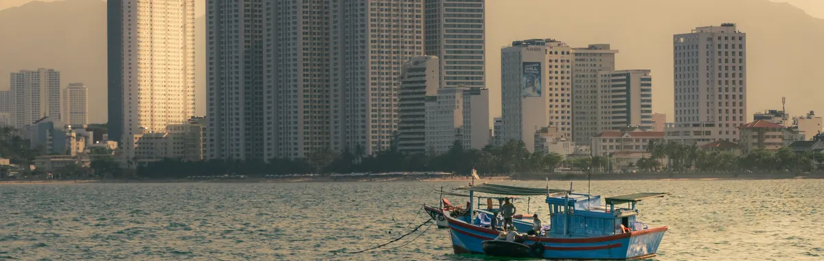 Explore the serene coastal skyline of Nha Trang with boats floating in the calm sea.