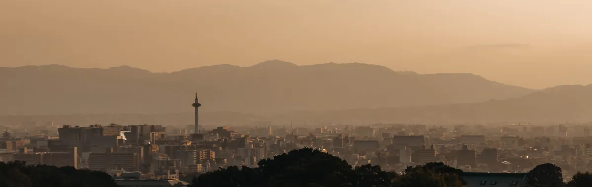 Breathtaking view of Kyoto cityscape with Kyoto Tower and surrounding mountains at sunset.