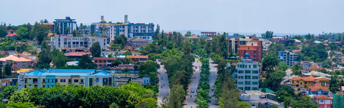 Panoramic view of Kigali cityscape featuring lush greenery and urban development under a sunny sky.
