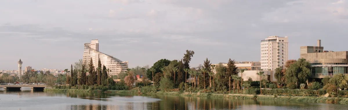 Peaceful river scene with contemporary buildings in Adana, Türkiye, reflecting tranquil ambiance.