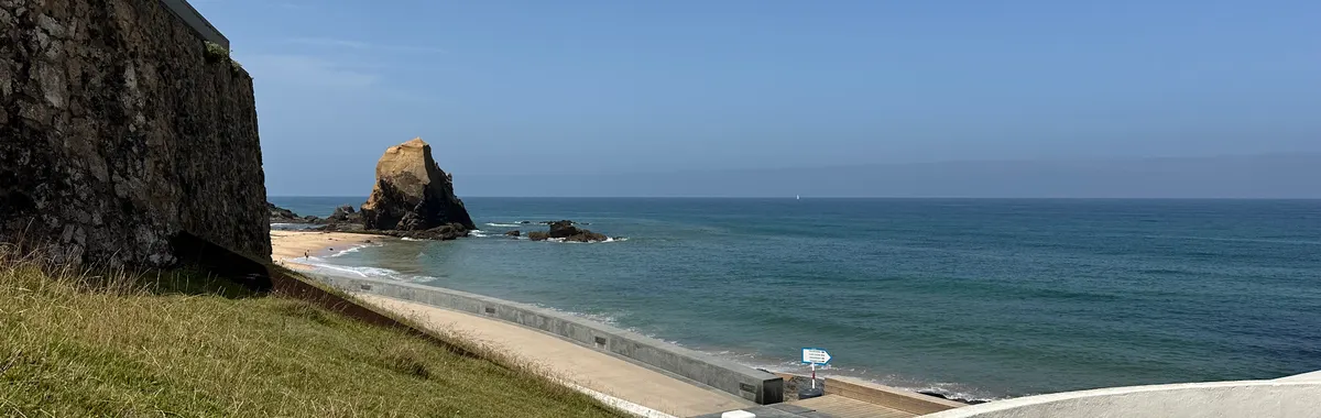 Beautiful sunny day at Praia do Porto Novo, Torres Vedras, Portugal. Blue sea, sandy beach, and rugged cliffs.