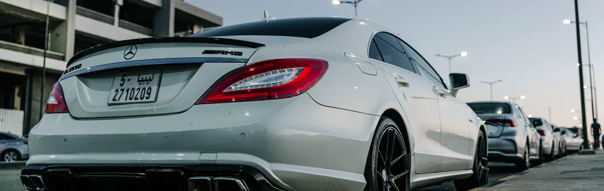 White Mercedes Benz CLS parked on an urban street in Tripoli, showcasing sleek design against a twilight backdrop.