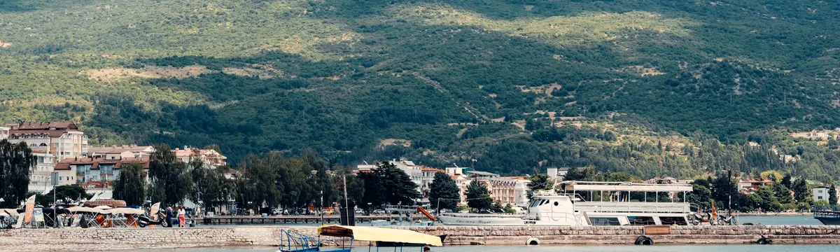 מקדוניה הצפונית: Peaceful scene of a boat on Lake Ohrid with a mountainous backdrop in North Macedonia.