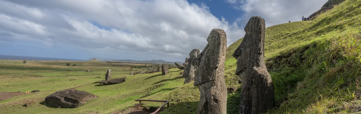 Explore the iconic Moai statues on Easter Island, Chile, surrounded by vast green landscapes and a bright blue sky.