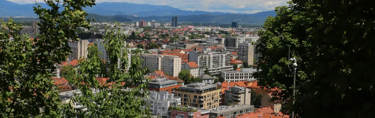 A vibrant cityscape of Ljubljana, Slovenia, framed by lush greenery and a clear sky.