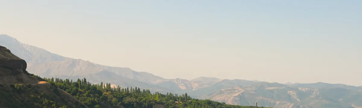 אוזבקיסטן: Tranquil view of a mountain lake surrounded by lush green hills in Tashkent Region, Uzbekistan.