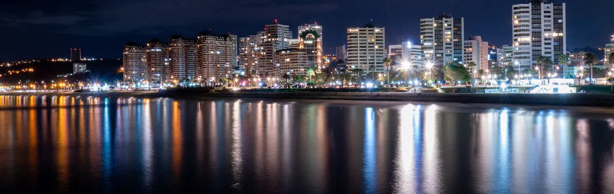 Captivating night cityscape of Viña del Mar with lights reflected over the ocean.