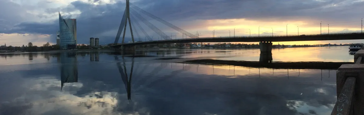 Beautiful sunset over Daugava River with a modern cable-stayed bridge and skyline reflections in Riga, Latvia.