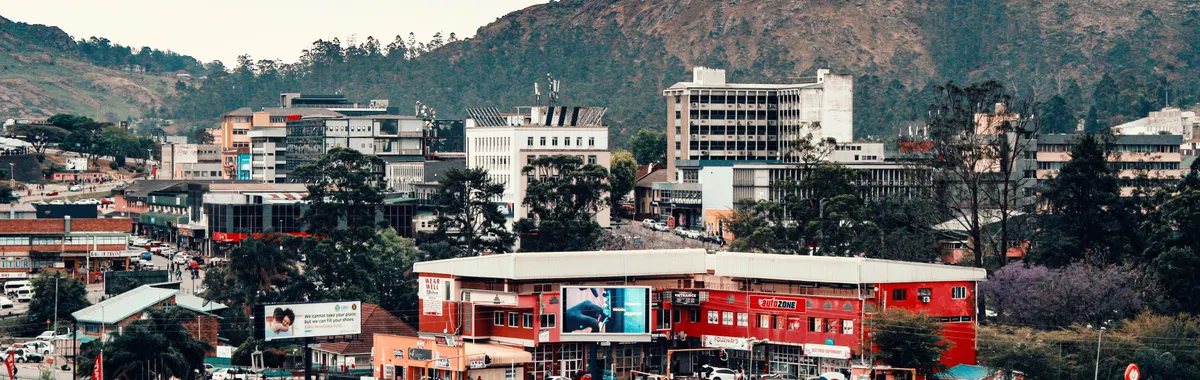 A vibrant cityscape of Mbabane, Eswatini, framed by scenic mountains.