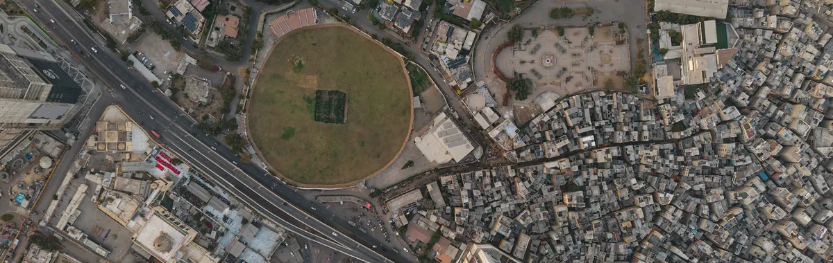 A detailed aerial shot of Karachi showing dense settlements and a distinct circular park, highlighting urban development.
