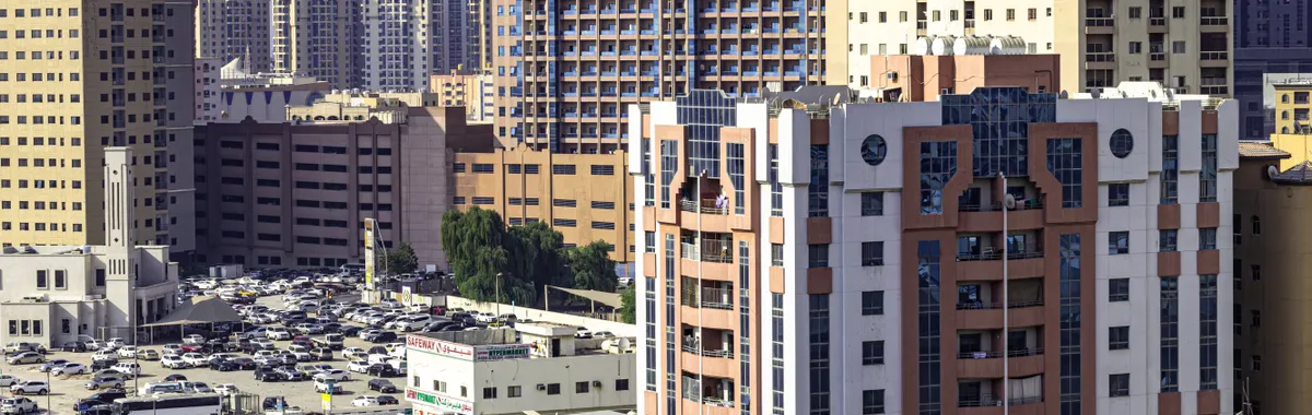 Aerial view of Ajman's urban skyline featuring highrise apartment buildings and busy streets.