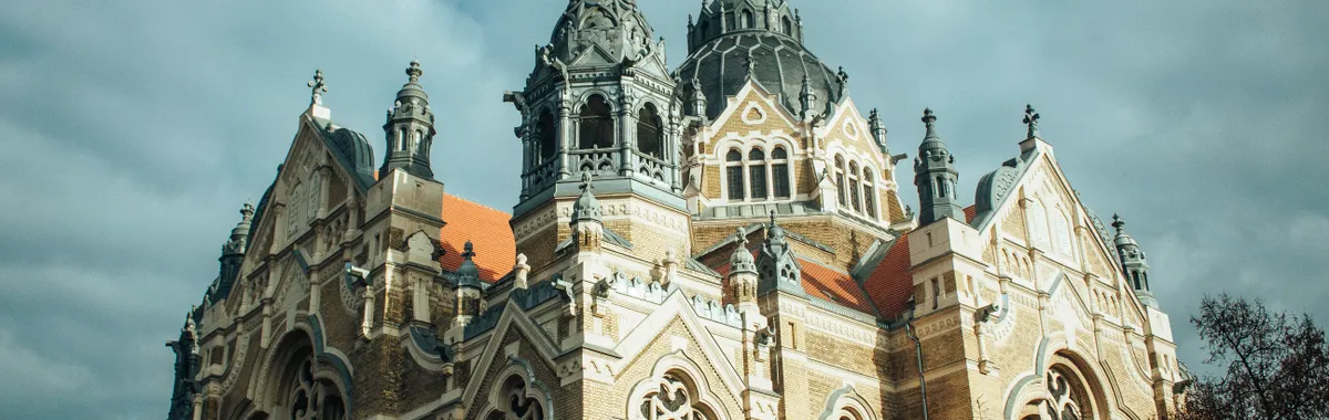 Capture of the stunning architectural detail of the New Synagogue under a cloudy sky in Szeged, Hungary.