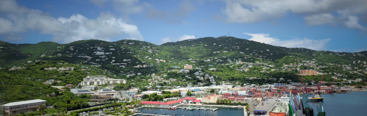 Aerial view of Charlotte Amalie Harbor in St. Thomas with vibrant buildings and lush green hills.