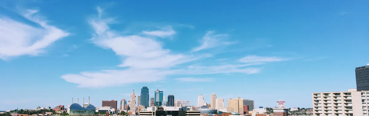 Wide-angle shot of Kansas City's skyline with clear blue skies and vibrant green foreground.