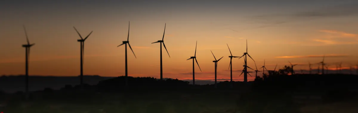 Silhouettes of wind turbines against a vibrant sunset in Lleida, Spain.