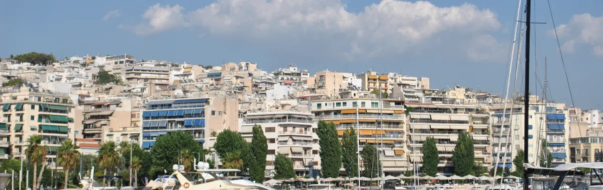 Picturesque scene at Piraeus Marina, Athens showing boats and vibrant city architecture.