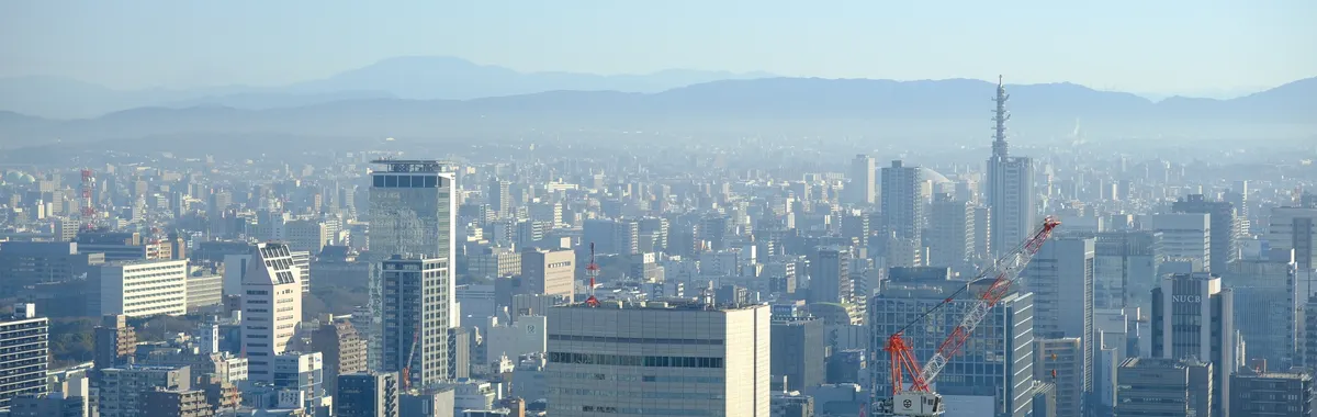 Breathtaking view of Osaka cityscape with skyscrapers and mountains in the background.