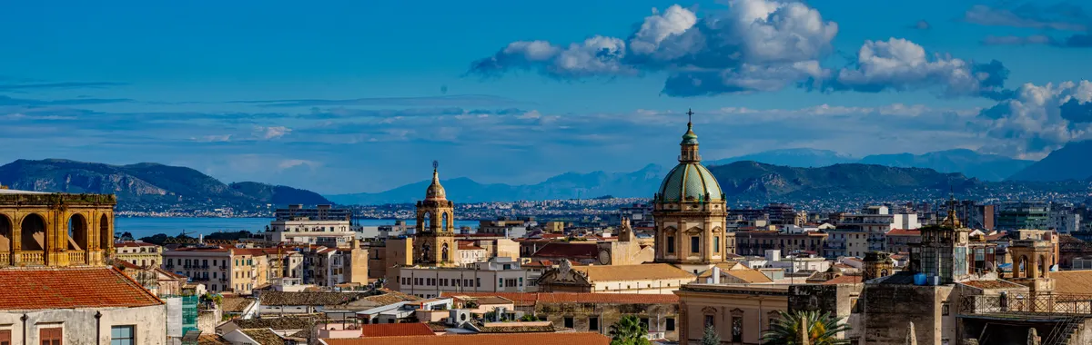 Discover the vibrant skyline of Palermo, Sicily capturing historic architecture beneath a bright blue sky.