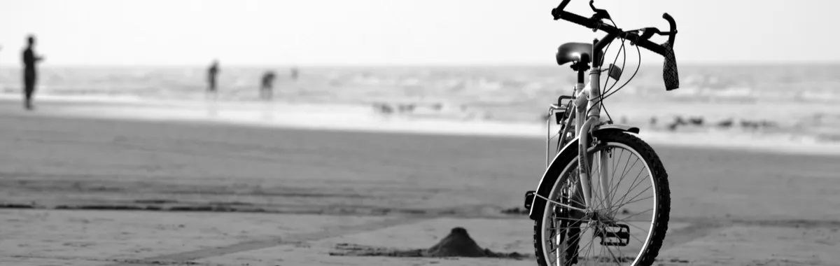 A black and white photo of a bicycle parked on Seeb beach, Oman, capturing the essence of solitude and peace.