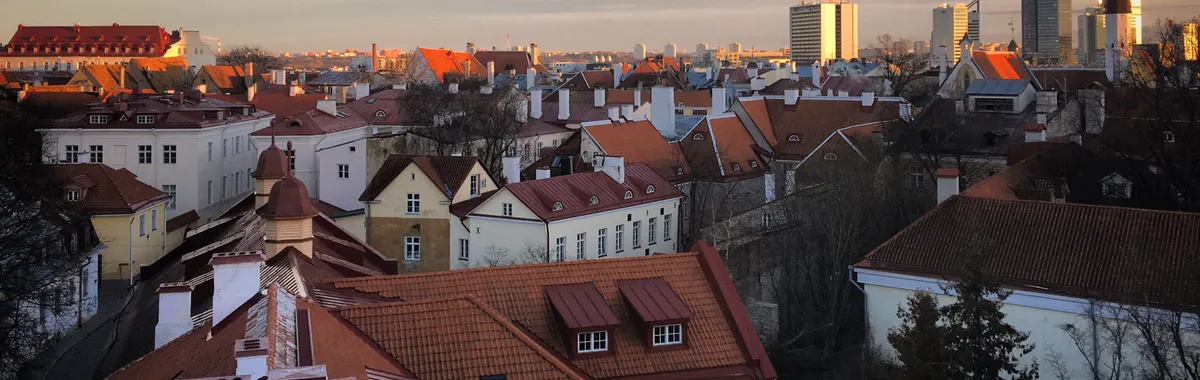 Stunning aerial view of Tallinn's Old Town with red rooftops and modern skyline at sunset.