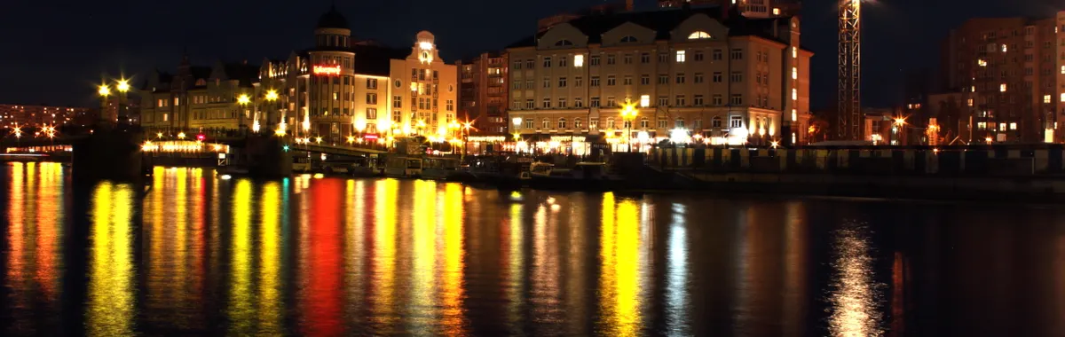 Beautiful night view of Kaliningrad's waterfront with city lights reflecting in the water.