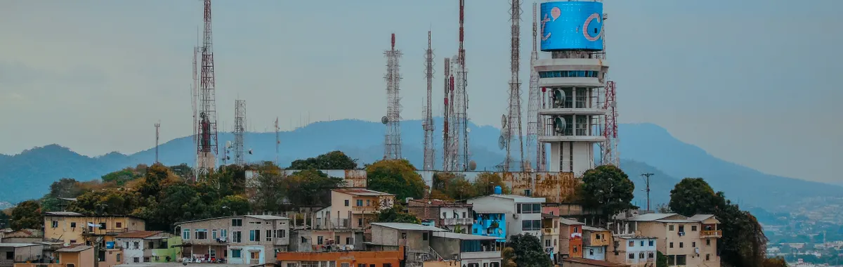 A vibrant view of Guayaquil's skyline with telecommunication towers over colorful hillside houses in Ecuador.